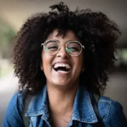 mujer sonriendo con gafas pelo rizado